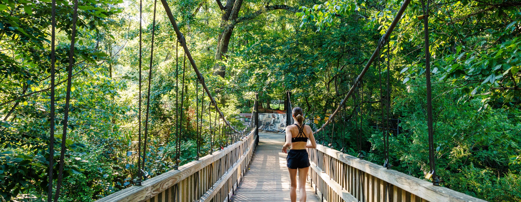 woman running on bridge through woods