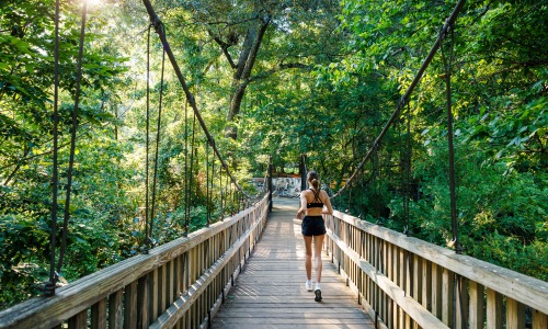 woman running on bridge through woods